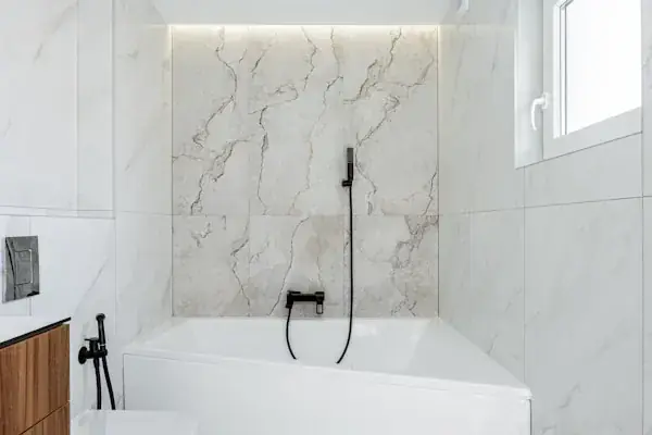 Modern bathroom with a glass-enclosed shower, freestanding bathtub, double-sink vanity with wood drawers, large mirror, and marble floor and walls.